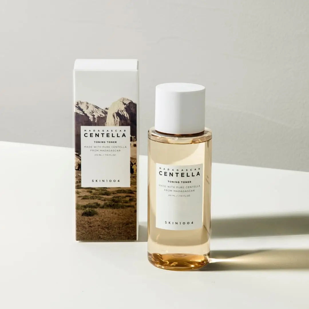 Clear bottle with golden liquid and white cap next to a white box featuring mountain imagery, both labeled Skin 1004 Madagascar Centella Toning Toner 210 ml.