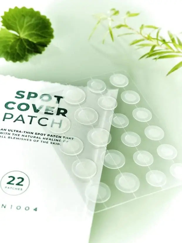 Transparent round spot cover patches on clear sheets with white packaging for Skin 1004 Magadascar Centella Tea-Trica Spot Cover Patch, placed next to green leaves.